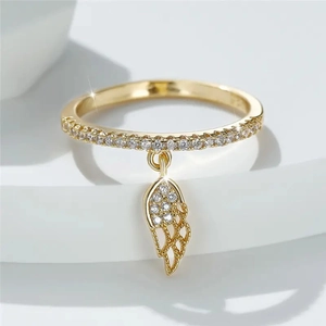 Macro detail of a gold wing pendant ring with sparkling cubic zirconia on a white stand