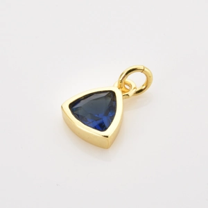 Macro view of a triangular dark blue gemstone pendant with a polished gold finish frame