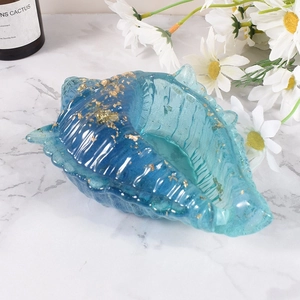 Blauwe hars schaal in schelpvorm met goudvlokken op een wit marmeren blad
