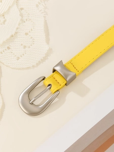 Detailed close-up of a bright yellow slim leather belt with a matte silver D-ring buckle