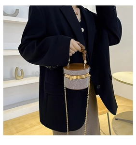 Detail of crystal-embellished cylinder evening bag with brown leather top and gold chain