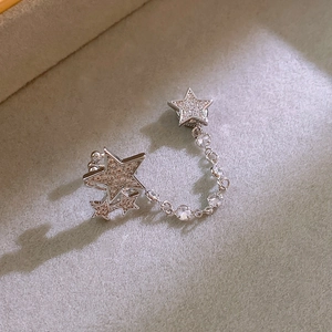 Detail of silver star earrings with zircon inlay and chain link on grey velvet