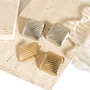 Textured square 18K gold and silver stainless steel earrings on a beige stone base