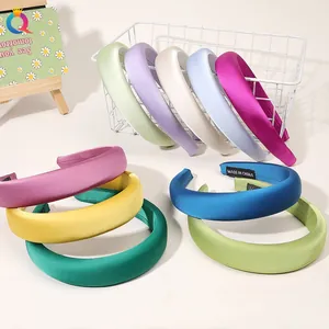 Detail of colorful sponge headbands in satin fabric displayed in a white wire basket