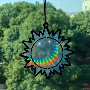 Close-up of a sun-shaped rainbow prism suncatcher reflecting holographic light on window