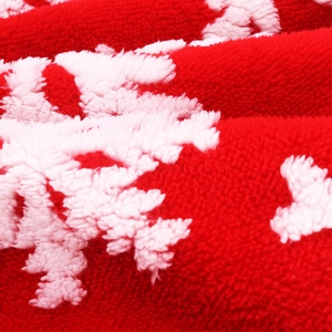 Detailed macro view of plush red Christmas tree skirt fabric with white snowflake pattern