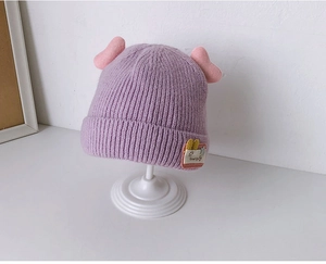 Detail of light purple knit baby hat with pink 3D ears and Good life patch decoration