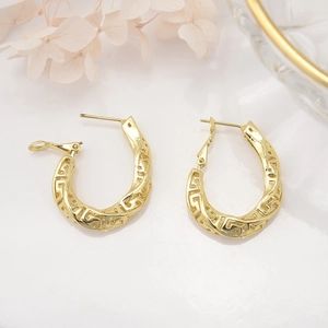 Macro detail of 18k gold plated hollow C-shaped earrings with Greek key pattern