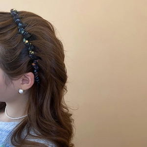 Close-up of a floral fabric headband with subtle colorful knit texture on a model