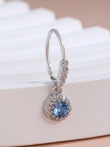 Macro view of a silver pendant featuring a round blue center stone and tiny white zircons