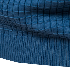 Vue détaillée du tricot bleu foncé montrant la texture gaufrée et les poignets côtelés
