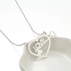 Collana con ciondolo a cuore geometrico argento e incisione LOVE su vassoio bianco