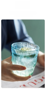 Close-up of glacier-textured glass cup with lime slices and refreshing ice water