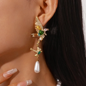 Detailed macro view of bird-shaped earring with colorful gems and drop pearl on model