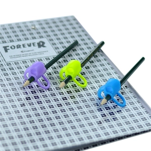 Three silicone pencil grips in purple, green, and blue on a notebook for writing posture