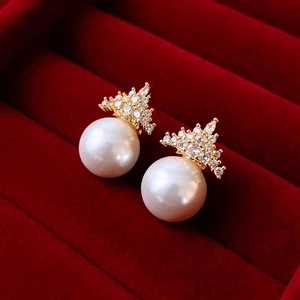 Close-up of elegant crown-shaped gold earrings with zircon crystals and white pearls