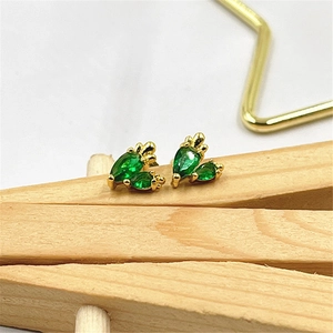 Elegant gold carrot shaped stud earrings with green zircon stones on wooden clip