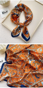 Detailed close-up of retro floral print silk scarf featuring vivid orange and navy blue patterns