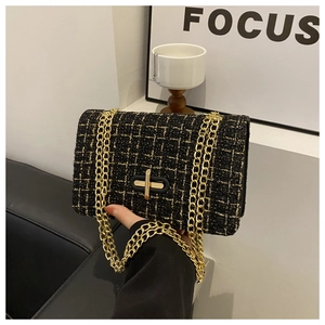 Detail of black tweed crossbody bag with gold chain strap and metallic rotary lock