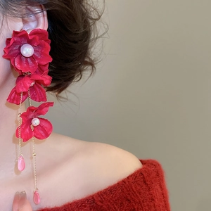Detail of red fabric flower earring with pearl center and dangling crystal tassel charms