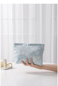 Close-up of light blue cosmetic bag featuring white swan jacquard and brand fabric label