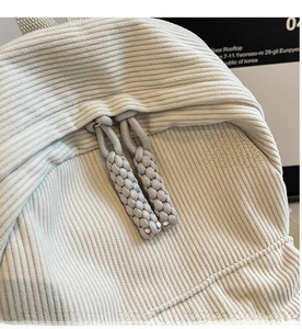 Detail of premium corduroy backpack featuring durable dual zippers and woven pullers