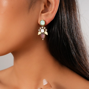 Detail shot of a golden multi-stone drop earring with pastel crystals on a model
