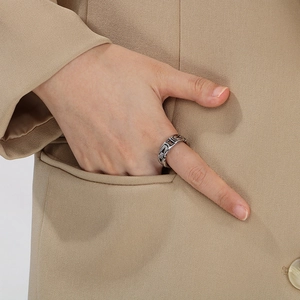 Detail view of a silver V-shaped weave ring on model wearing a beige blazer suit