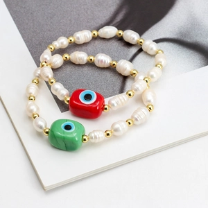 Detail of freshwater pearl bracelets with red and green evil eye charms on a magazine