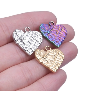 Détail de pendentifs en forme de cœur en argent, or et arc-en-ciel avec gaufrage floral