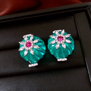 Vue macro de boucles d'oreilles en pierre verte avec motifs floraux en argent et diamants