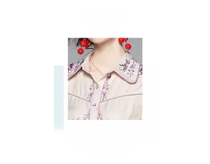 Detail of floral purple embroidery and golden buttons on beige dress collar neckline