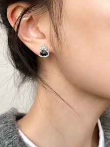 Detailed close-up of a silver gourd stud earring with black and clear crystals on model