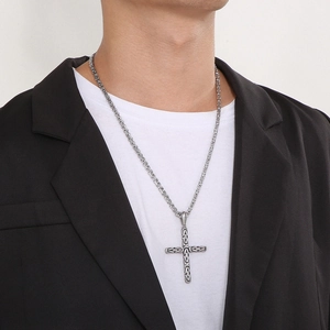 Close-up of silver-tone stainless steel cross necklace on male model wearing a suit