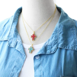 Close-up of layered gold cross necklaces with red and sky blue square-cut zircon stones