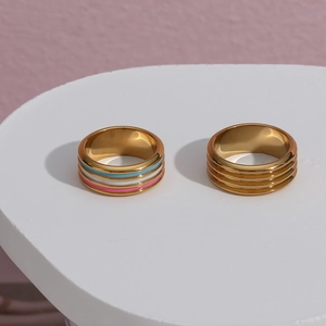 Detailed shot of two gold rings with enamel colorful stripes and grooved textures