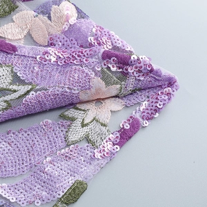 Detailed macro shot of purple sequin embroidery and floral lace on a sheer mesh fabric