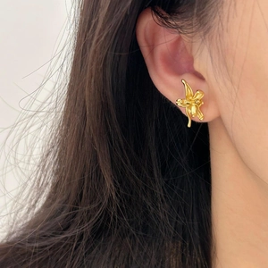 Elegant gold flower stud earrings in 925 sterling silver worn on a woman's ear