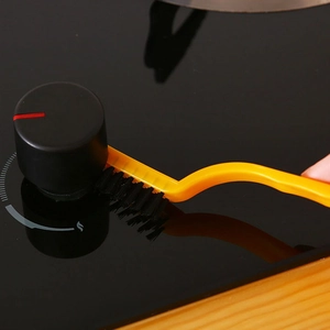 Yellow kitchen crevice brush cleaning gas stove knobs with durable black bristles