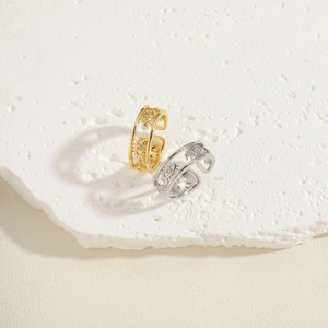 Close-up of gold and silver evil eye heart rings on a white textured stone surface