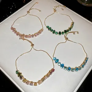 Bracelets dorés ajustables avec zircons ovales colorés sur présentoir en cuir blanc