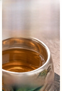 Detailed macro view of an insulated teacup with elegant green dragon patterns