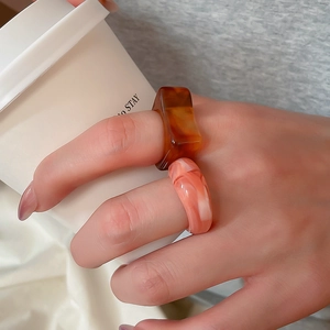 Detail of a resin ring set featuring amber square and pink marble patterns on hand