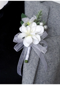 Elegant white fabric boutonniere with pearls and ribbons on a grey suit lapel