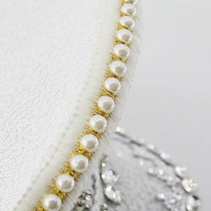 Detail of white sequins and faux pearls with gold thread on the festival navy hat