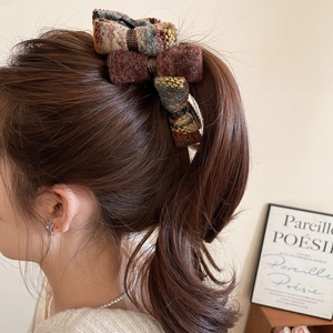 Close-up of retro tweed bow hair claw clip showing textured multi-color fabric weave