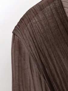 Makro-Detail der dunkelbraunen Faltenstoff-Textur für halbtransparente Blusen