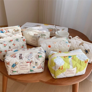 Quilted cotton cosmetic bags with cute animal prints arranged on a wooden table
