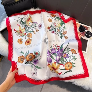 Dettaglio di un foulard quadrato in finta seta leggera con stampe floreali e bordi rossi