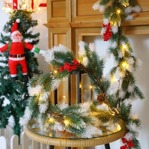 Close-up of frosted pine wreath with red berries, pinecones and warm LED fairy lights